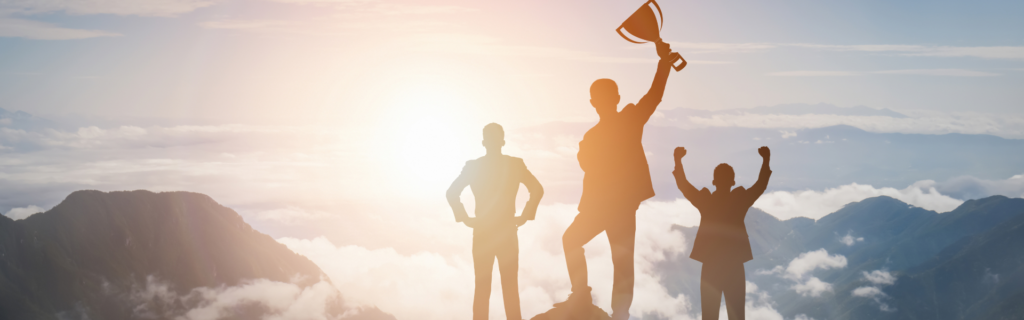 Three people standing on top of a mountain and the person in the middle is holding up a trophy.