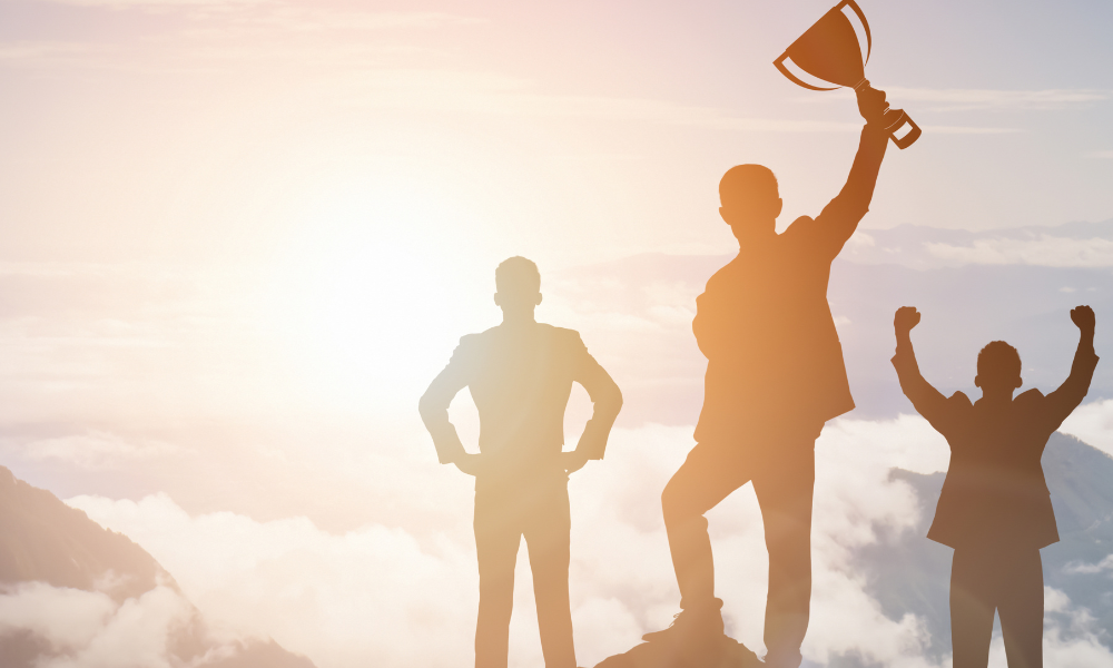 Three people standing on top of a mountain and the person in the middle is holding up a trophy.