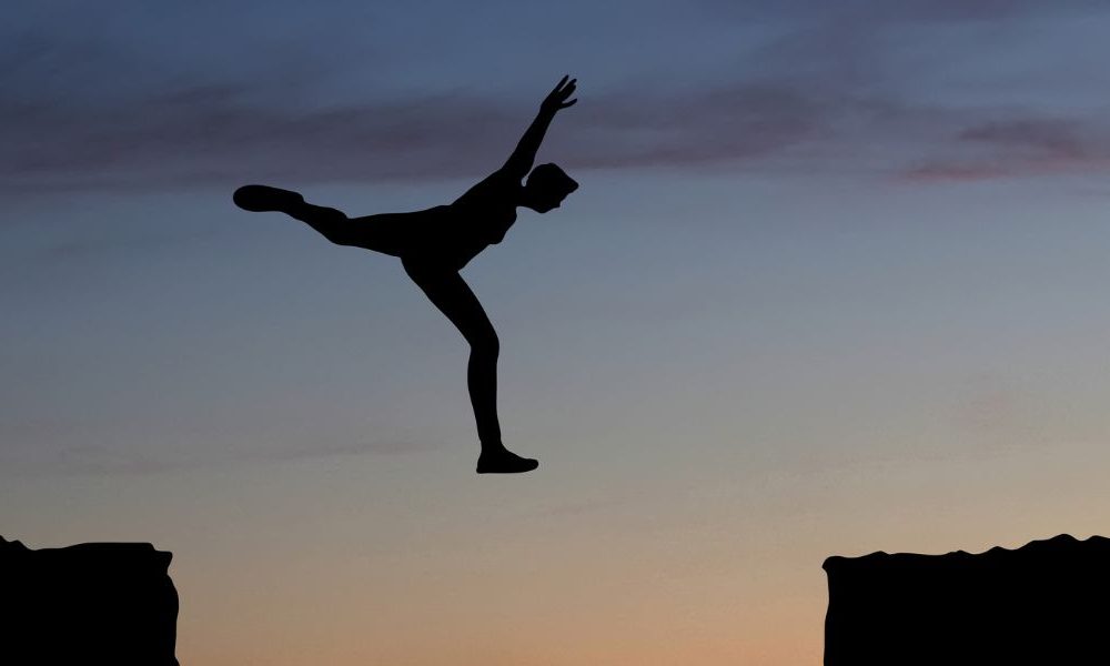 A person leaping between rock ledges.