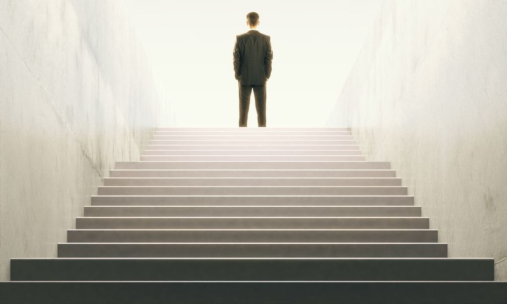 A man in a suit standing at the top of a staircase.