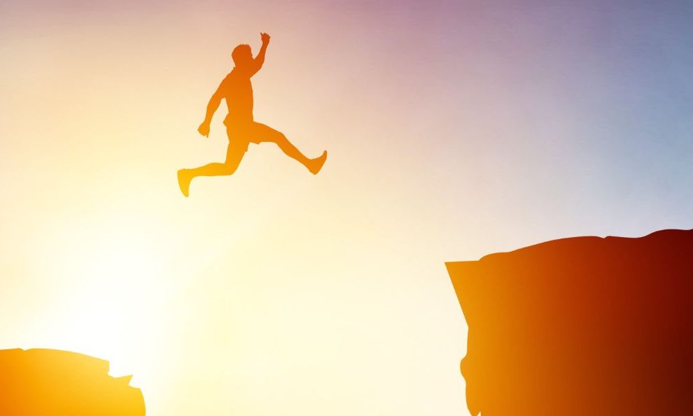 A person leaping between rock ledges.