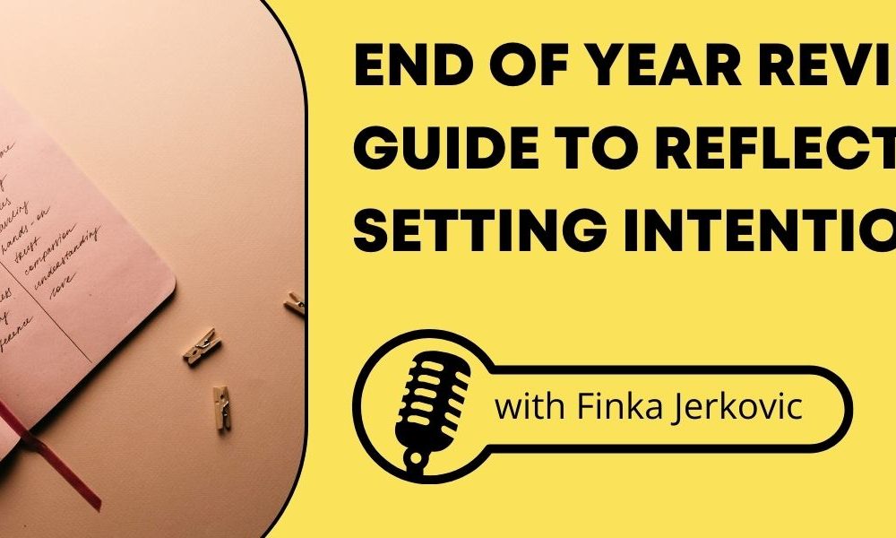 A notebook open on a table with a pen next to a yellow background with the words, "End of Year Review: Your Guide to Reflecting and Setting Intentions for 2025."