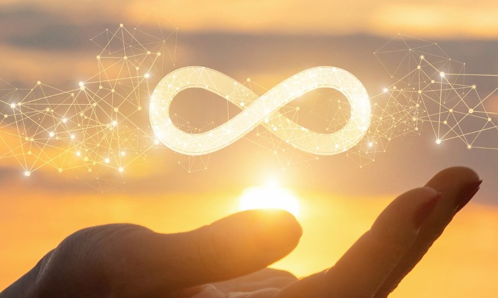 A person holding a lit up infinity sign in their hand.