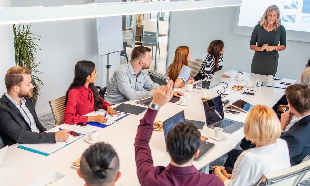 A group of people sitting at a table in an office board room.