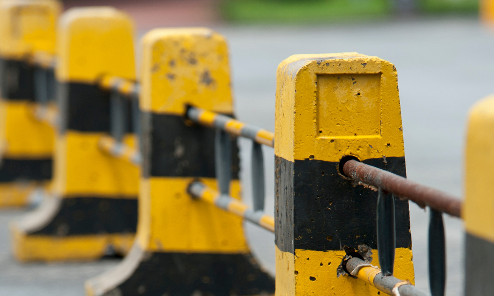 A line of yellow and black roadblocks on a road.
