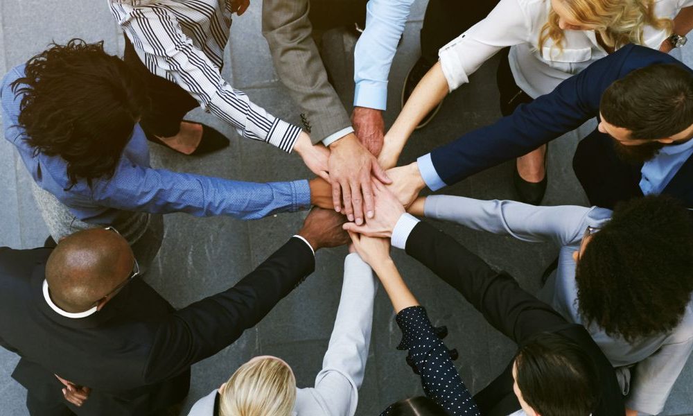 A group of employees connecting their hands in a circle.