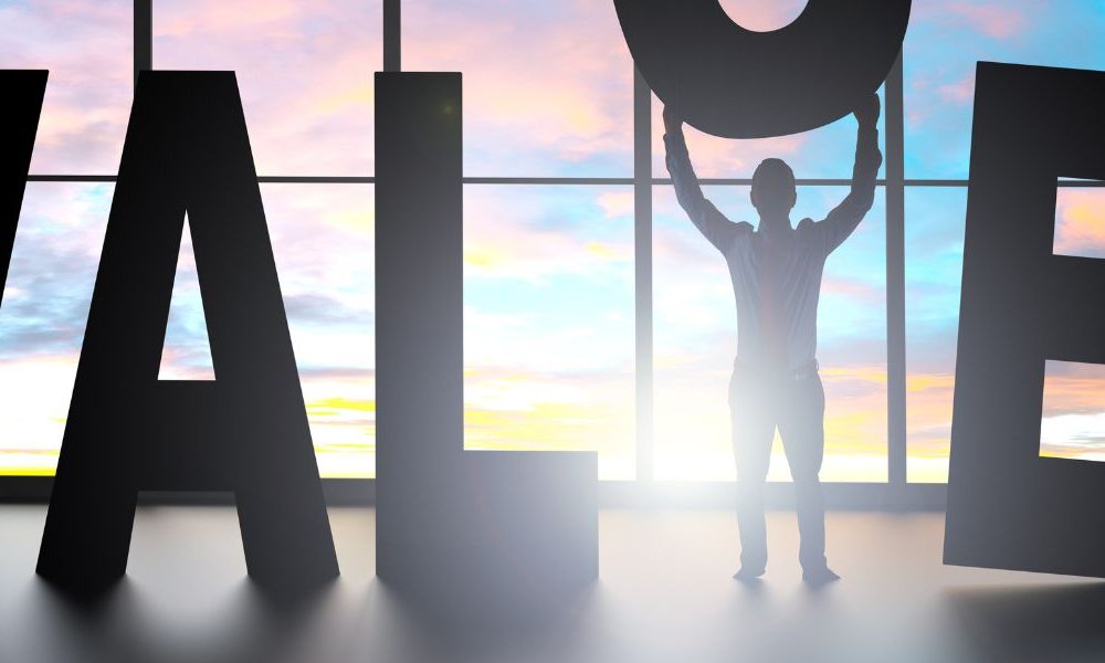 Business people moving together letter figures of the word value in front of a window.
