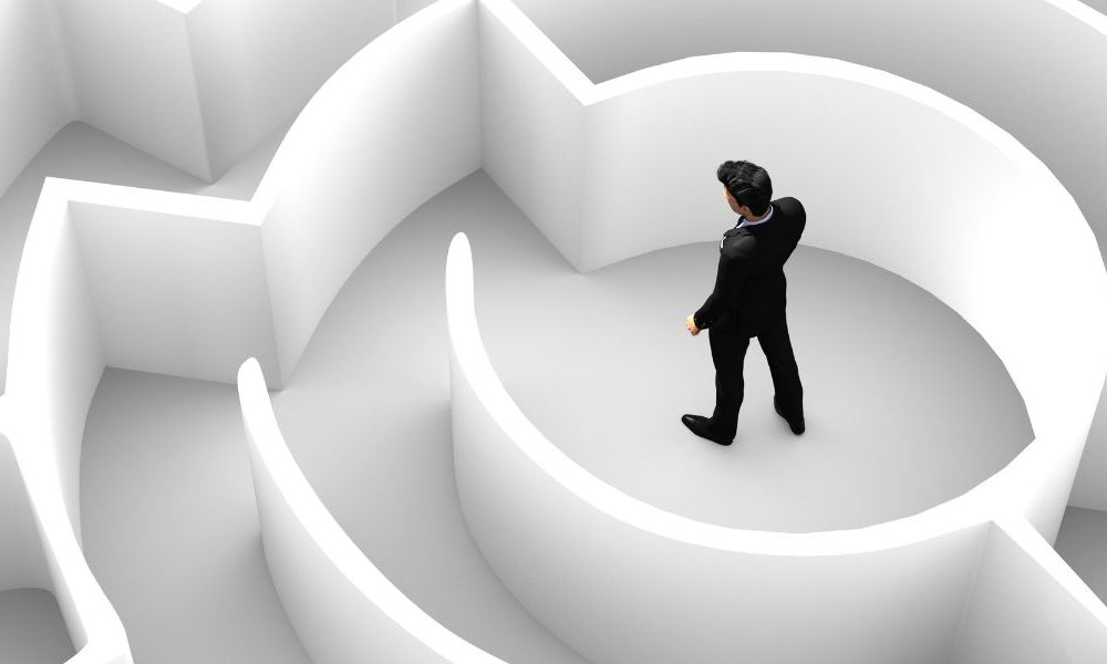 A man in a suit standing in the middle of a white maze.